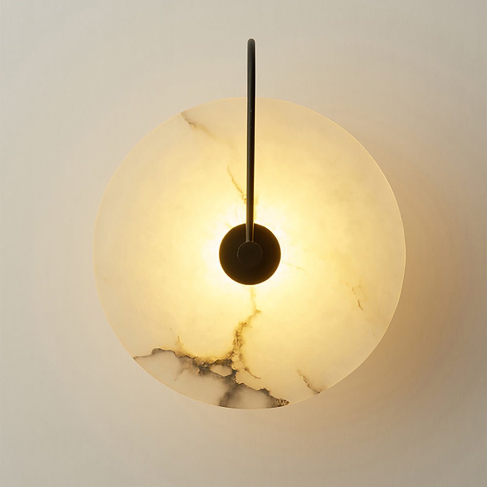 White marble wall sconce glowing on a pale wall