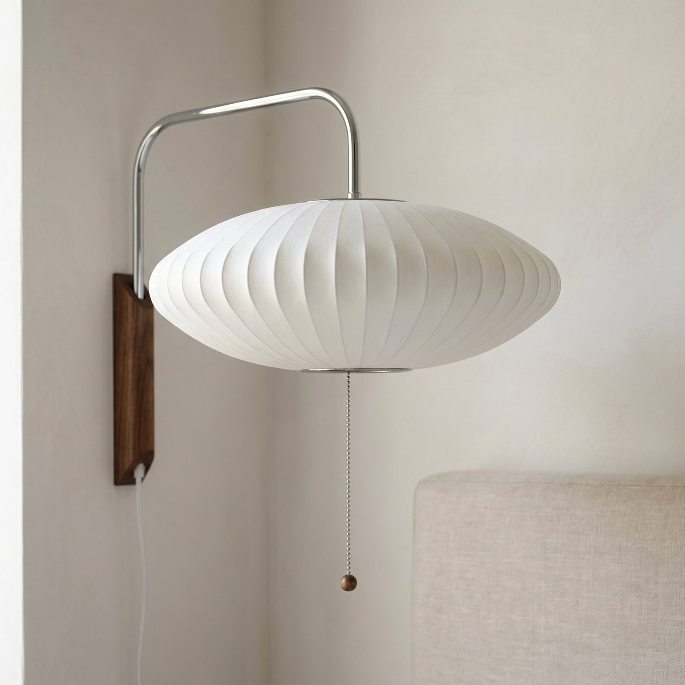 Mid-century cigar-shaped wall sconce glowing on a living room wall